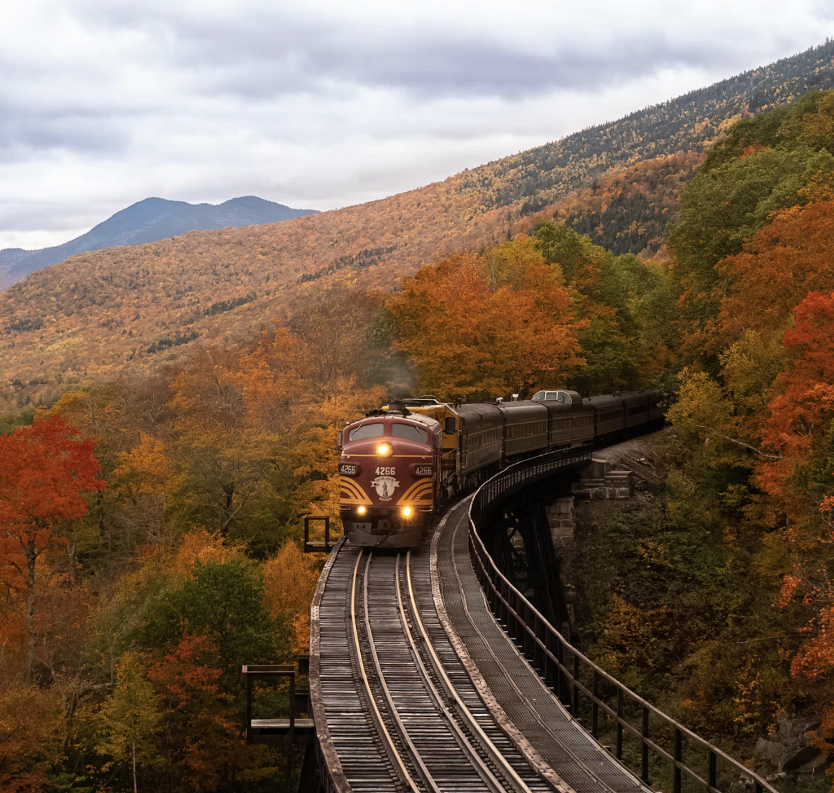 Autumn train crossing a railway bridge through New Hampshire mountains
