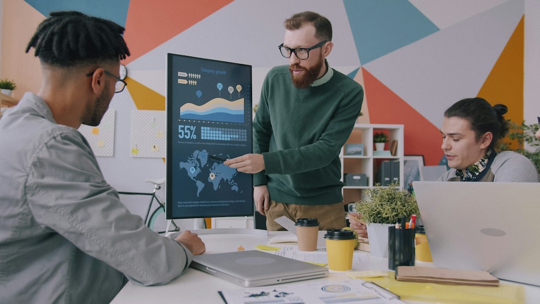 A presenter points to data charts on a monitor.