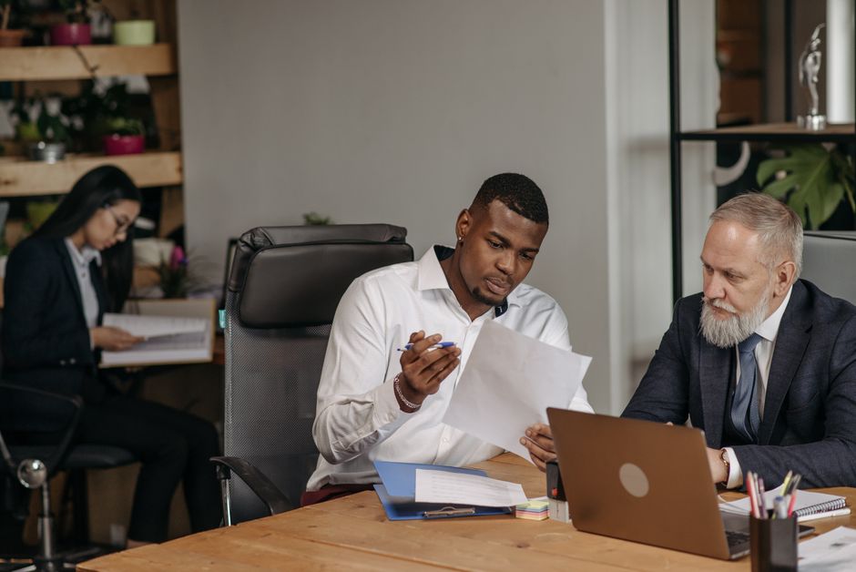 Business professionals discuss documents in a modern office.
