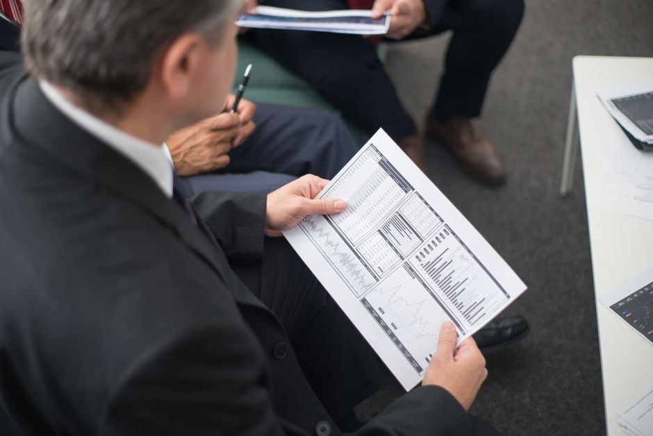 Business leaders review financial documents during a meeting.