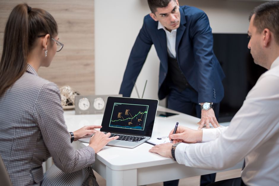 Professionals analyze stock market trends on a laptop.