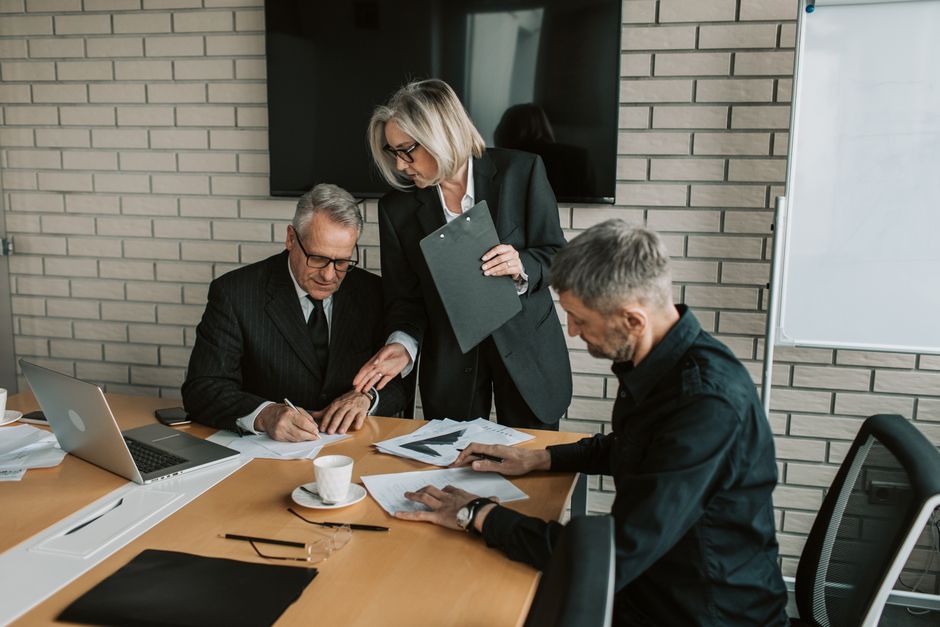 Professionals discuss and sign documents in an office.
