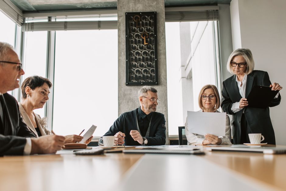 Professionals discuss documents in a modern meeting room.