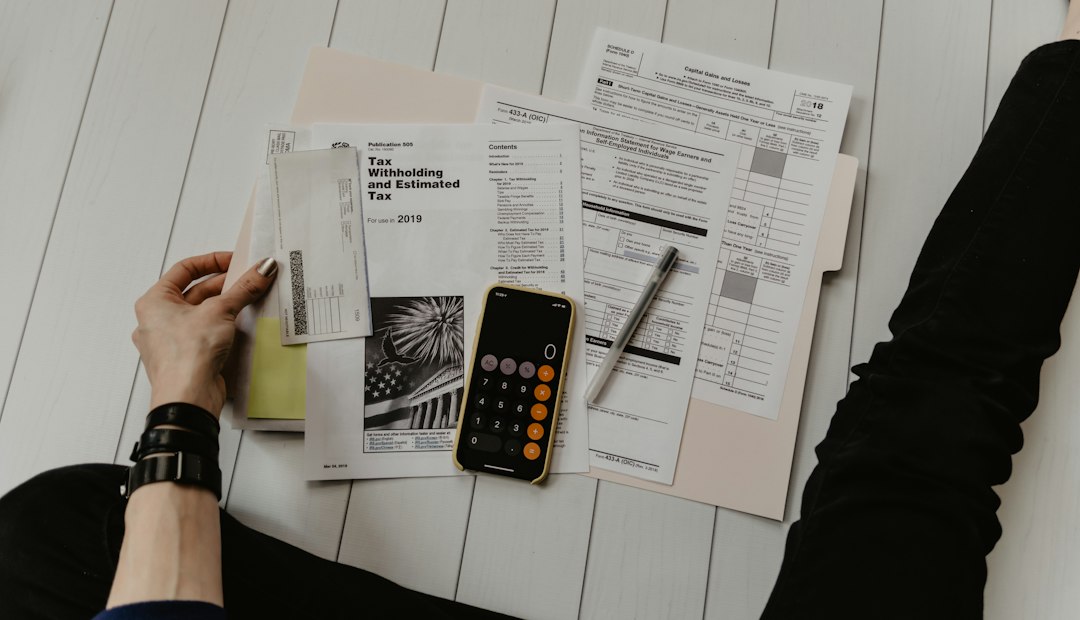 A person checks paperwork beside a calculator.