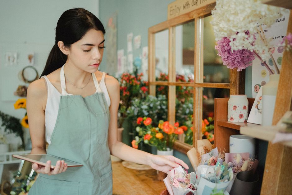 A florist checks an order on a tablet in a flower shop.